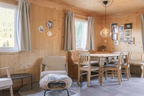 A wooden interior with a dining table, chairs, a sofa, and a small round table. - Cabin in Annaberg with swimming pool (Annaberg)