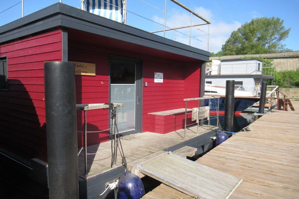 Un edificio rojo con un muelle, un letrero que dice 'Kaddis Inn' y una ventana pequeña.