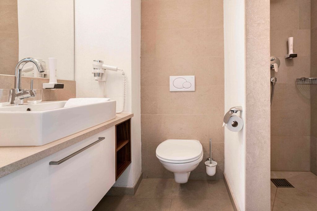 A modern bathroom with a sink, toilet, and shower.