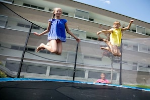 Two children jumping on a trampoline with a building in the background. - Apartment in Radstadt with swimming pool (Radstadt)