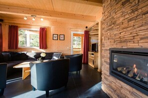 A cozy living room with a fireplace, a sofa, and a television. - Cabin in Turrach with sauna and balcony (Turrach)