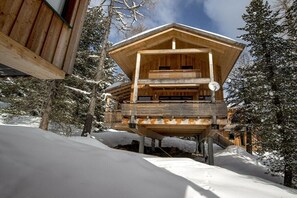 A wooden chalet with a balcony, surrounded by snow-covered trees. - Cabin in Turrach with sauna and balcony (Turrach)