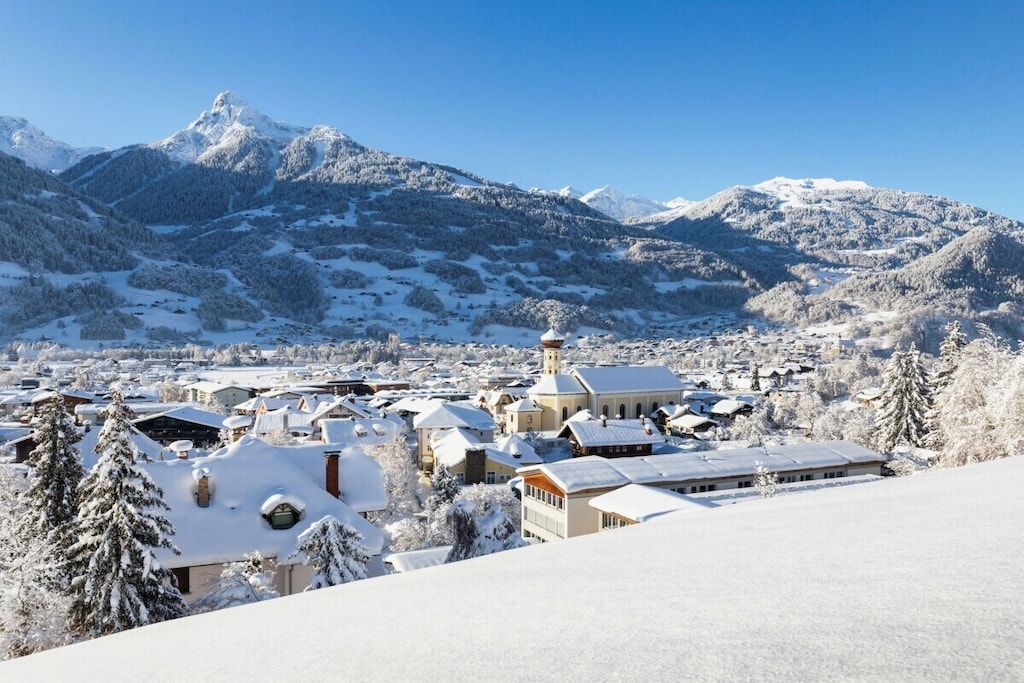 A snow-covered town with buildings and mountains in the background.