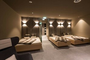 Ein modernes Zimmer mit drei Betten, jedes mit einem individuellen Kopfteil, und einem großen Fenster, das für natürliches Licht sorgt.