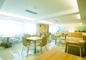 A modern dining area with multiple tables and chairs, a kitchen in the background, and large windows allowing natural light. - City Comfort Inn Wuhan Xudong (Wuhan)
