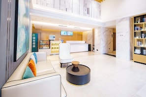 A modern hotel lobby with a reception desk, seating area, and a bookshelf. - City Comfort Inn Wuhan Xudong (Wuhan)