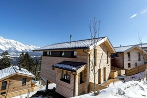 Eine Holzhütte mit geneigtem Dach, umgeben von schneebedeckten Bergen.