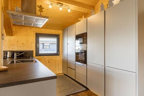 Eine moderne Küche mit Holzwänden, einem Einbauofen und einem Fenster.