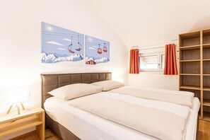 Ein Schlafzimmer mit einem Bett, einem Nachttisch, einem Fenster mit Vorhängen und einem Wandbild.