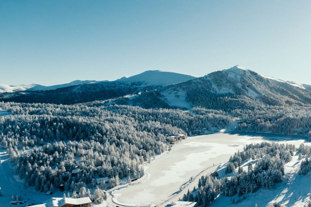 Paesaggio montano innevato con cielo sereno.