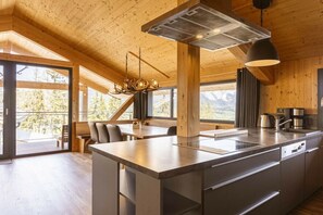 A modern kitchen with a large island, wooden ceiling, and large windows. - Cabin in Pichl near Schladming with sauna (Pichl bei Schladming)