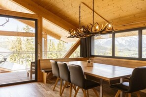 Ein Holzinterieur mit einem Esstisch, Stühlen und einer Deckenleuchte.