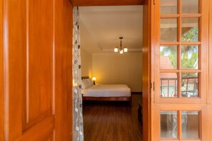 A bedroom with a bed, a nightstand, a lamp, and a chandelier. - Kibo Homes Moshi (Moshi)