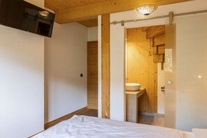 A bedroom with a bed, a television mounted on the wall, and a wooden ceiling. - Cabin in Pichl near Schladming with sauna (Pichl bei Schladming)