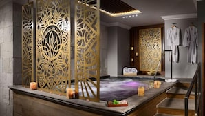 Zona de spa con hidromasaje, paneles decorativos y albornoces en un perchero.