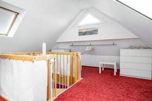Et børneværelse med tremmeseng, et lille bord og en hvid kommode.