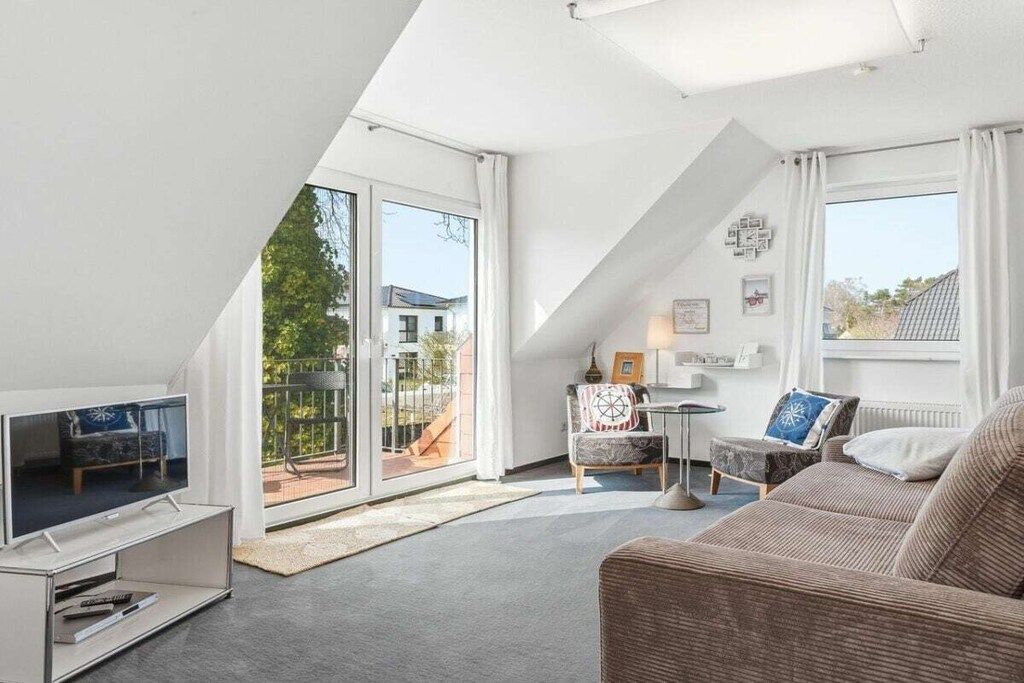 Ein modernes Wohnzimmer mit Fernseher, Sofa und Blick ins Freie.