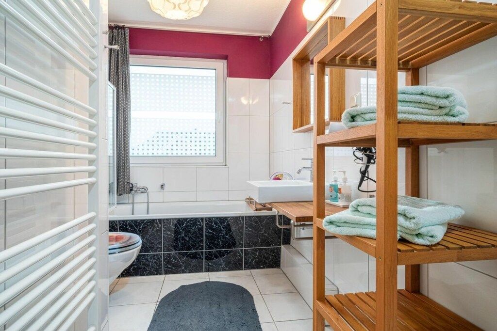 Een badkamer met een bad, toilet en een houten plank met handdoeken.