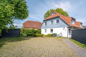 A two-story house with a red-tiled roof, a paved driveway, and a bicycle parked outside. - Ohana holiday apartment (Zingst (Ostseeheilbad))