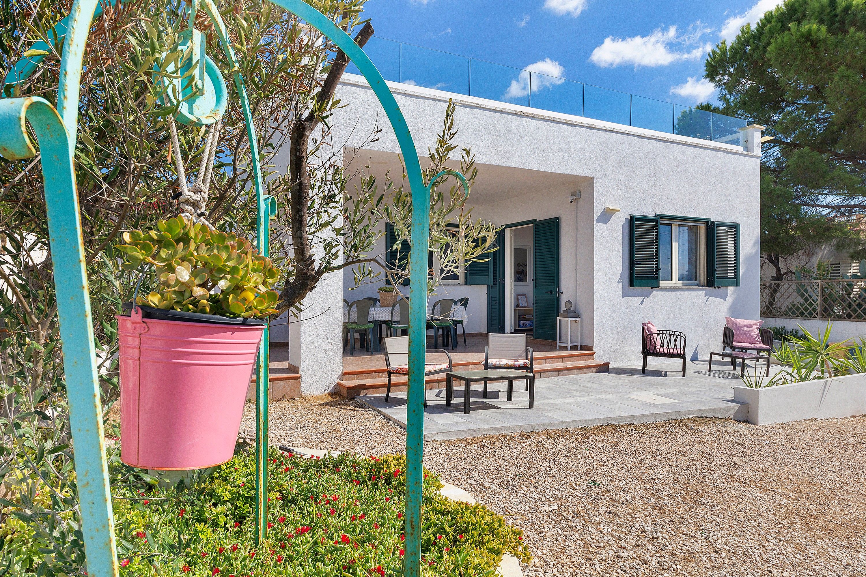 A modern house with a patio area, outdoor furniture, and a garden with potted plants.