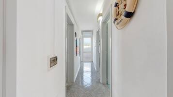 A hallway with a tiled floor, white walls, and a door at the end.