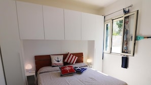 A bedroom with a bed, a nightstand, a window, and a wall-mounted mirror. - Villa 'Stella' with Sea View, Wi-Fi and Air Conditioning (Torre Vado)