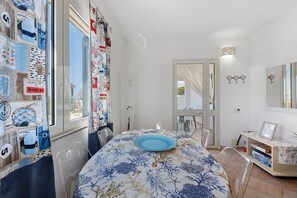 Ein Zimmer mit Esstisch, Stühlen, Kleiderhaken und einer Tür mit Spiegel.
