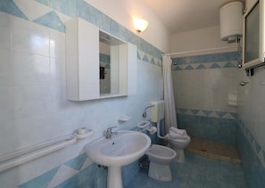 A bathroom with a sink, bidet, toilet, and a mirror.