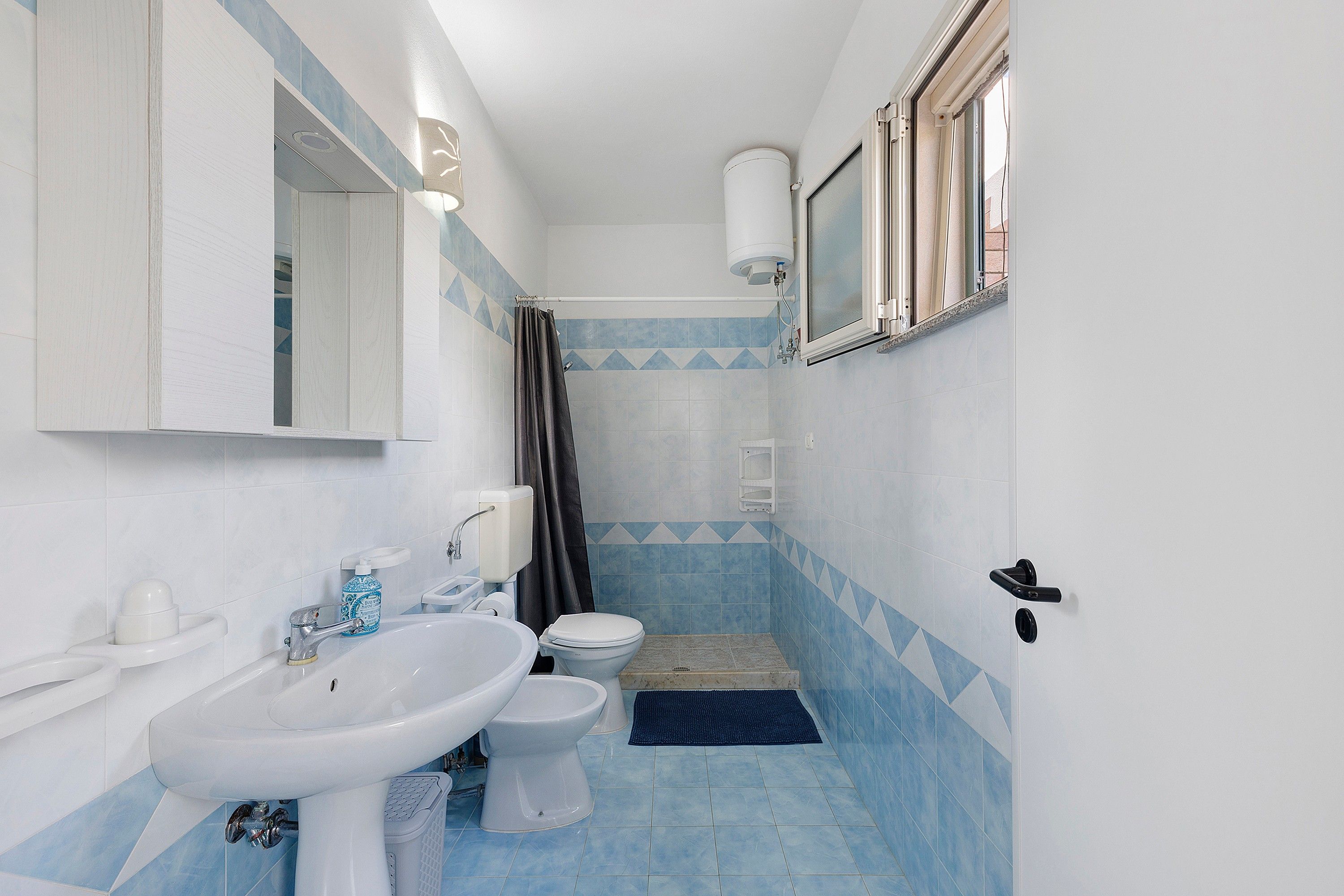 Une salle de bain avec un lavabo blanc, des toilettes et un espace douche.
