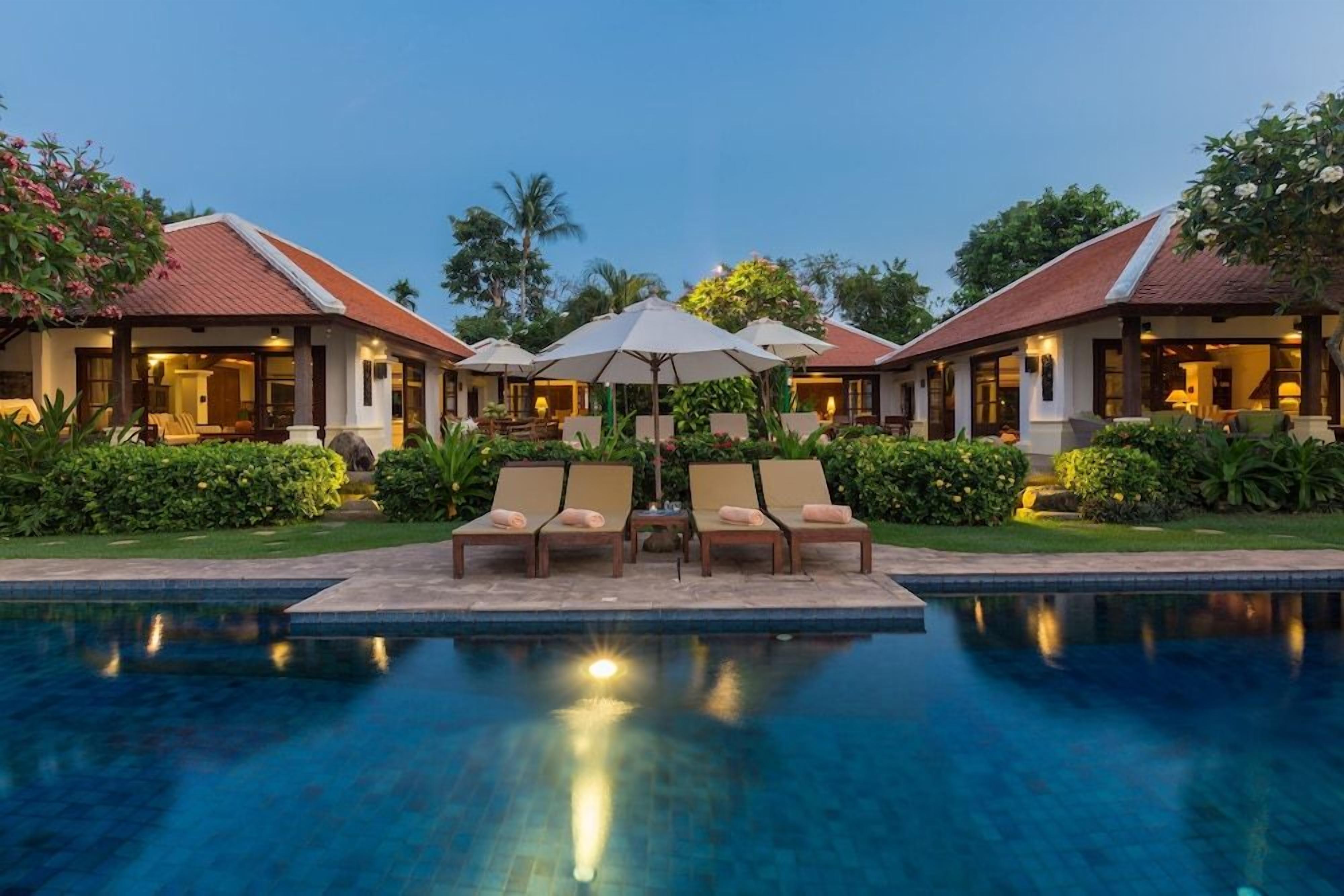 A resort with a swimming pool, lounge chairs, and umbrellas.