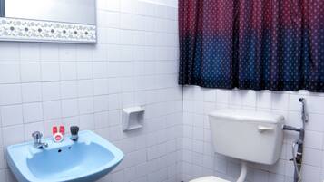 A bathroom with a white toilet, a blue sink, and a mirror with a floral border.