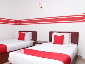 Ein Hotelzimmer mit zwei Betten, jeweils mit einer roten und weißen Bettdecke, und einer Wand in Rot gehalten.