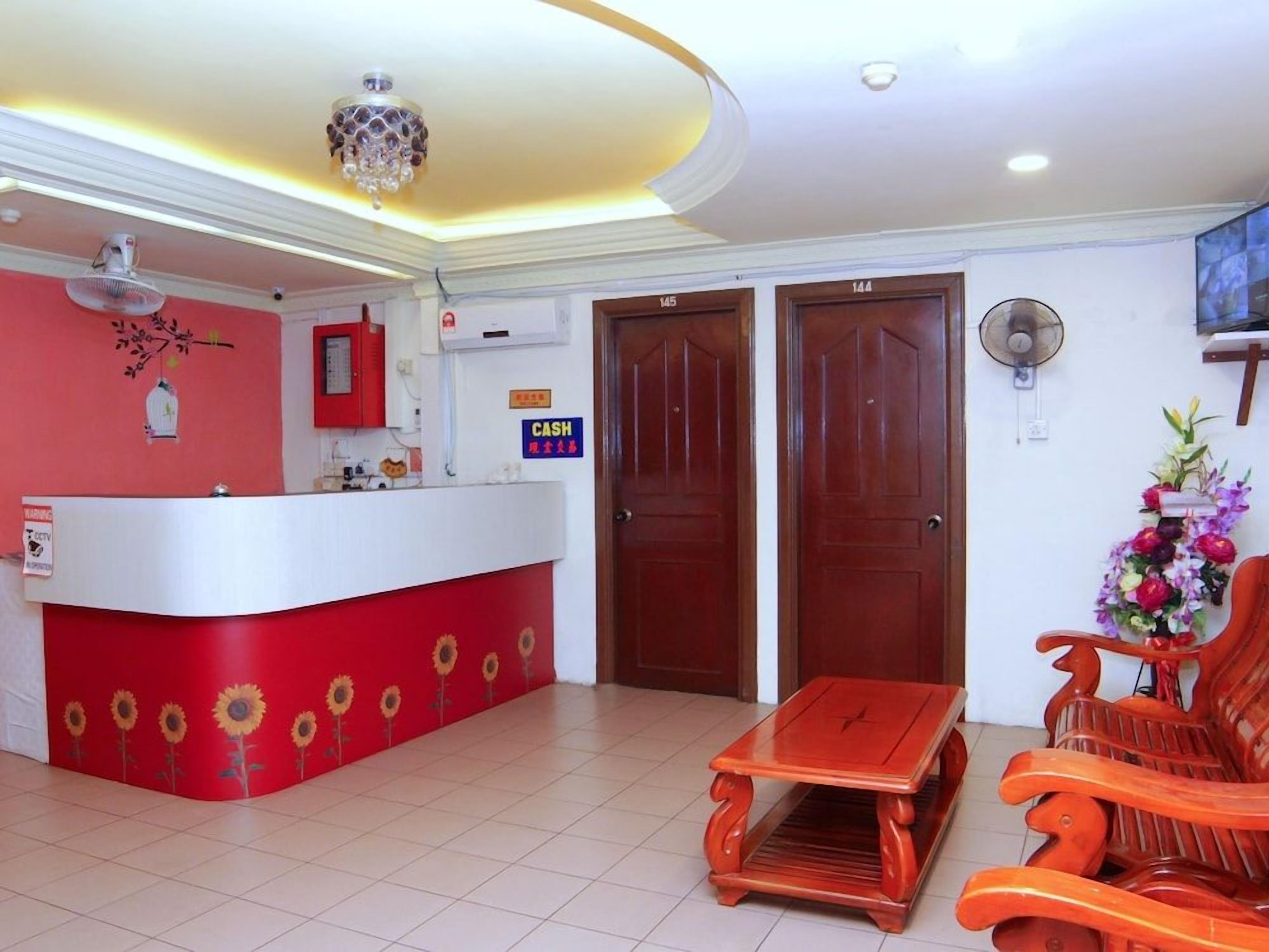 A reception area with a red counter, wooden doors, a fan, and a wooden bench.