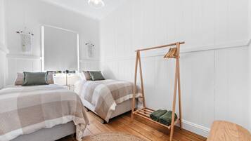 A bedroom with two beds, a wooden swing chair, and a large mirror.