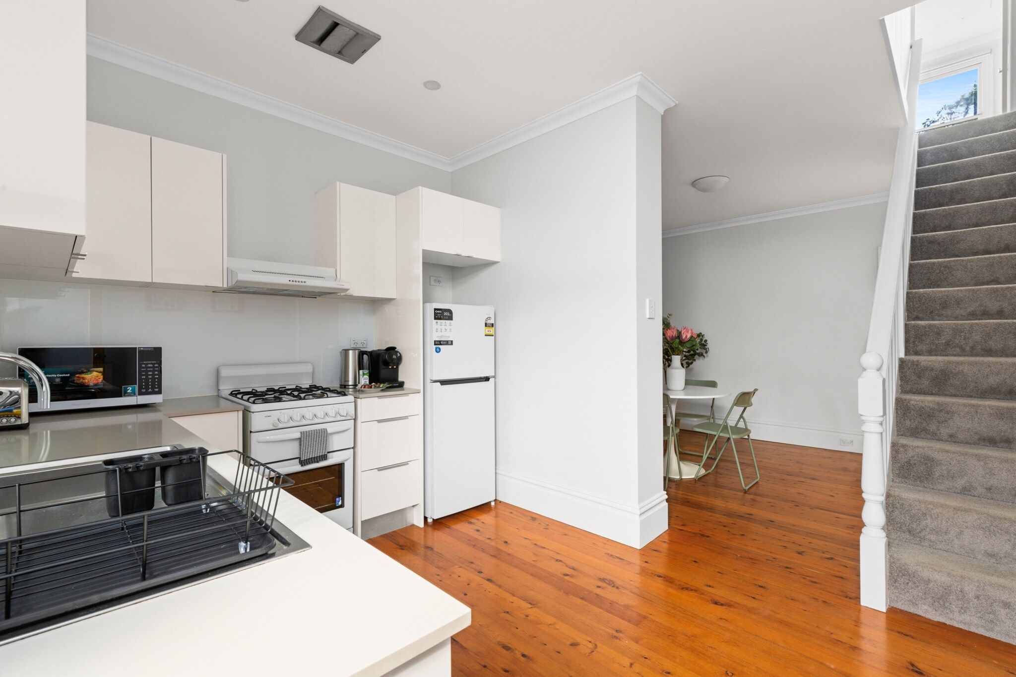 A modern kitchen with white cabinetry, a stove, a microwave, and a refrigerator.