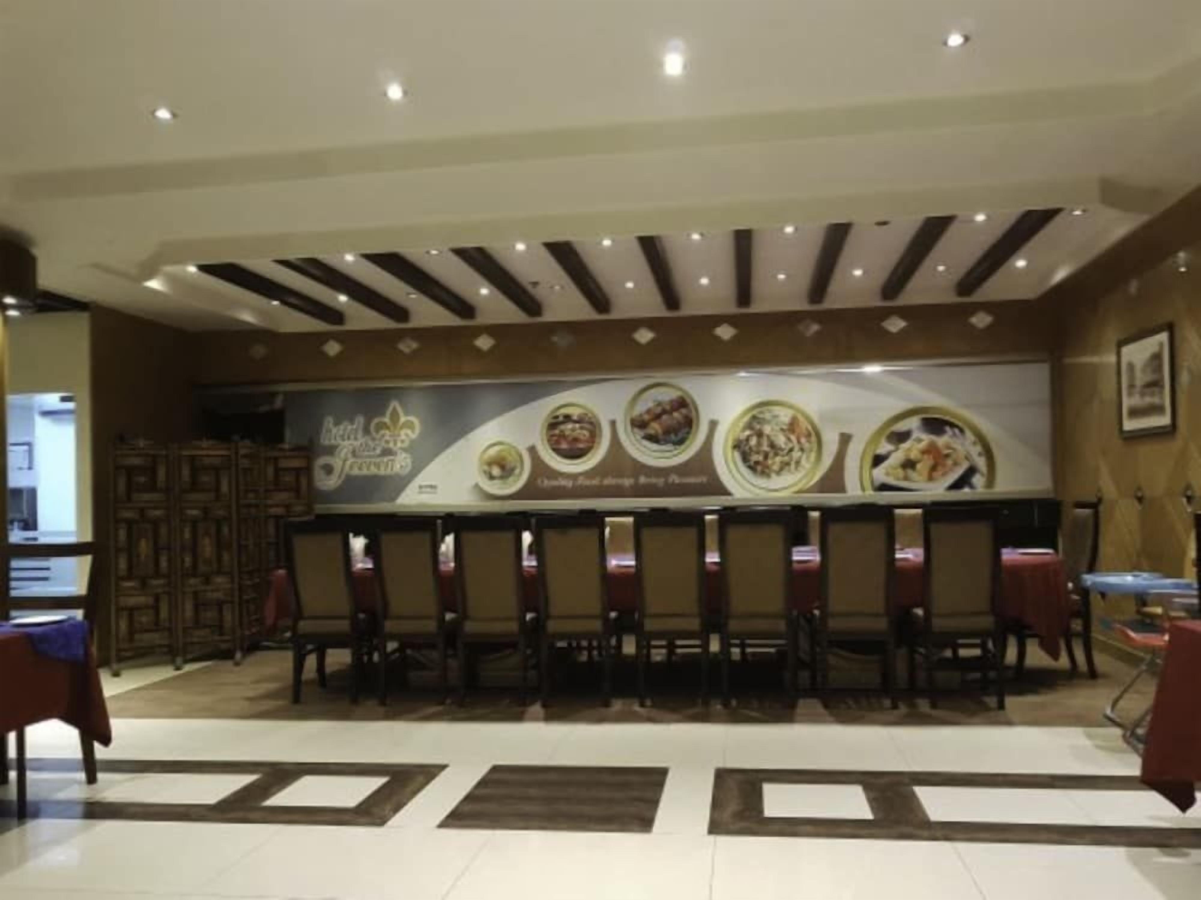 Un restaurante con una larga barra y varias sillas, un techo decorativo y un cartel que anuncia comida.