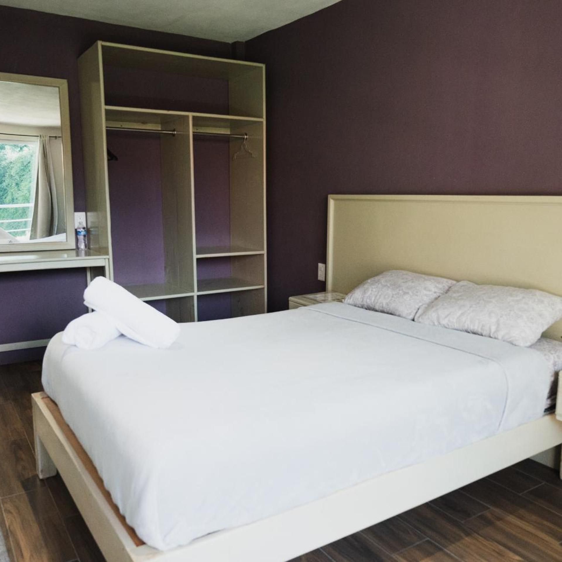 Un dormitorio con cama, armario y ventana.