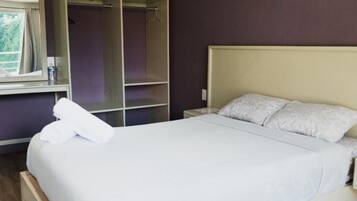 Un dormitorio con cama, armario y ventana.