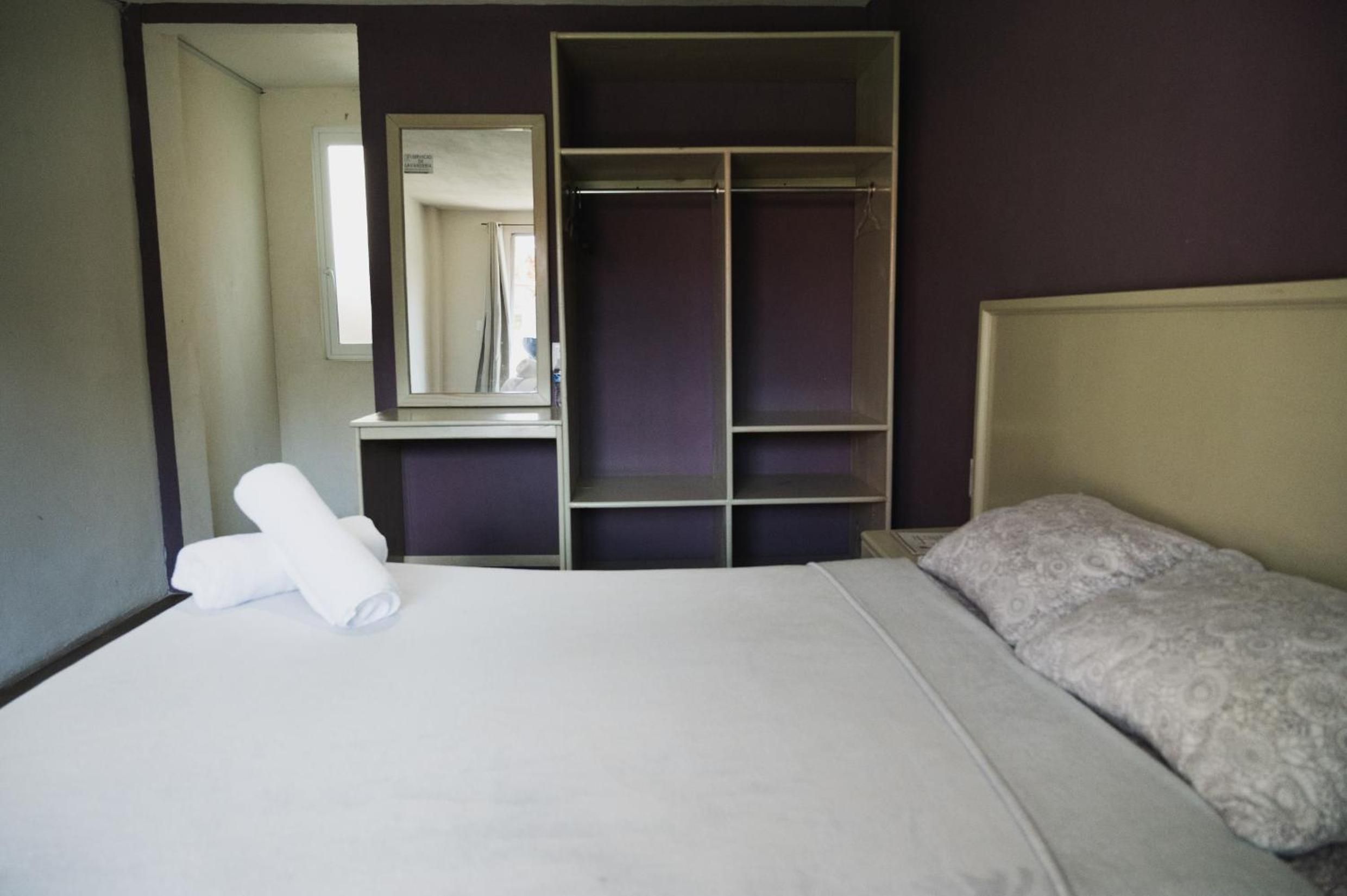 Una habitación de hotel con una cama, un armario y un espejo.