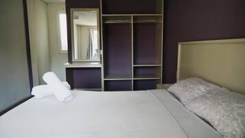 Una habitación de hotel con una cama, un armario y un espejo.