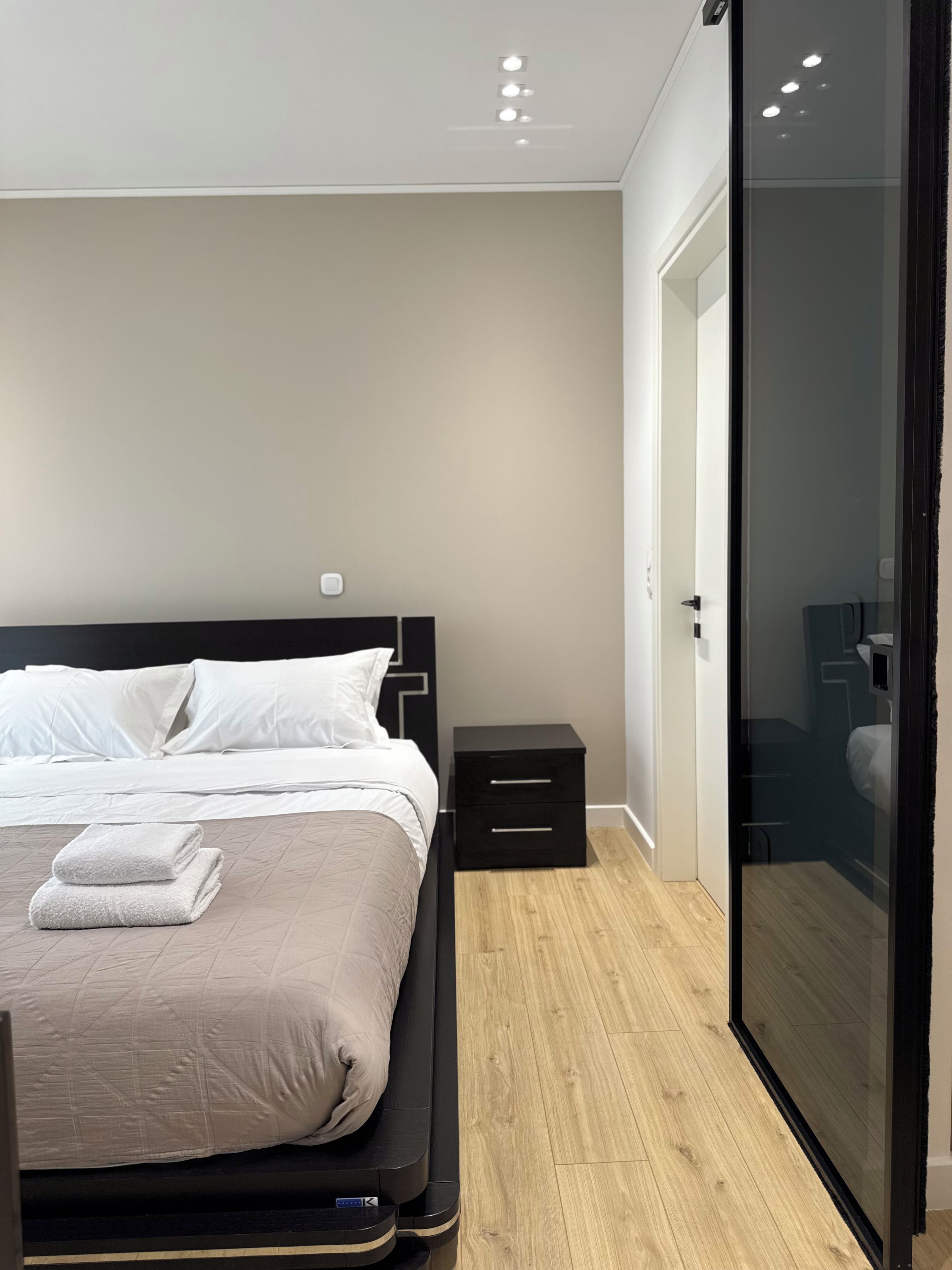 A modern bedroom with a bed, bedside tables, and a sliding door leading to a bathroom.