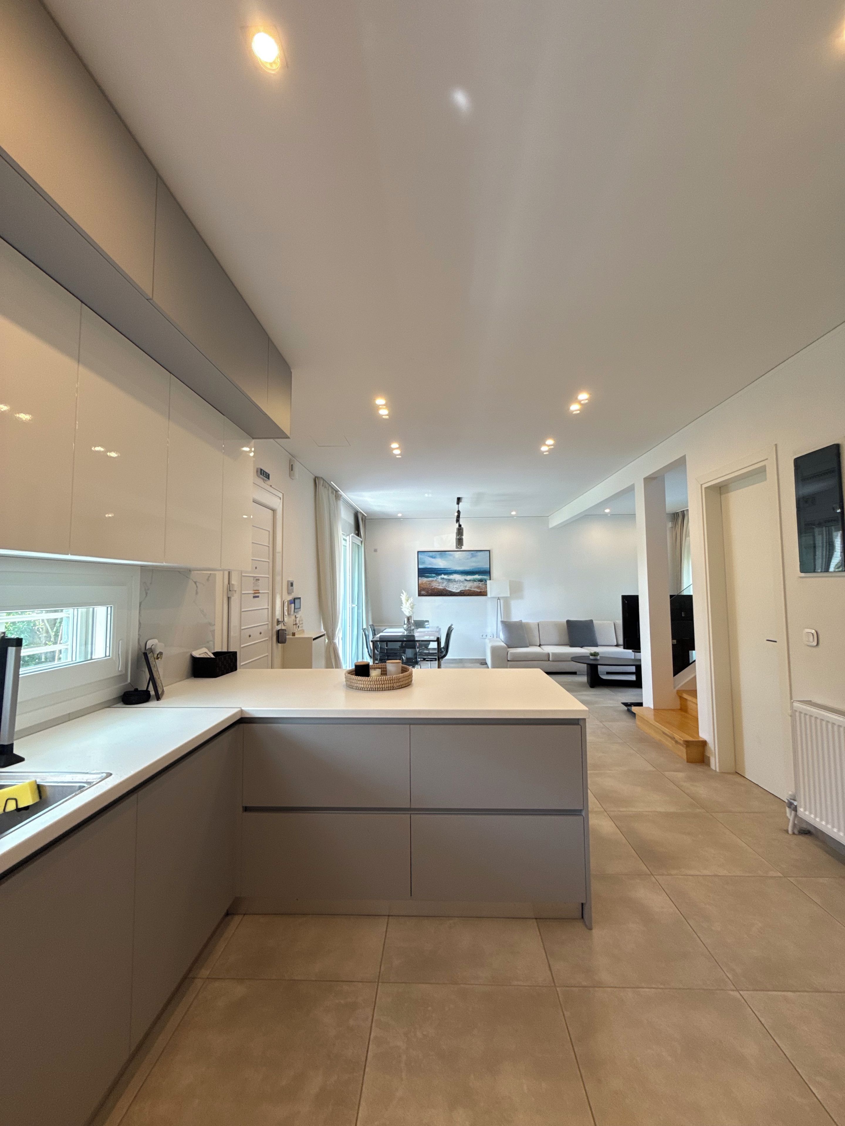 A modern kitchen with a central island, built-in appliances, and a dining area with a view.