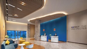 A modern reception area with a blue accent wall, a marble reception desk, and a seating area with sofas and ottomans. - Holiday Inn Express Guiyang Qingyan an IHG Hotel (Guiyang)
