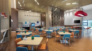 A modern restaurant with wooden floors, blue and orange chairs, and a variety of table shapes. - Holiday Inn Express Guiyang Qingyan an IHG Hotel (Guiyang)