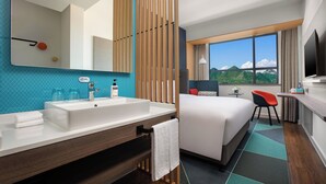 A hotel room with a large bed, a bathroom with a sink and mirror, a desk with a chair, and a window with a mountain view. - Holiday Inn Express Guiyang Qingyan an IHG Hotel (Guiyang)