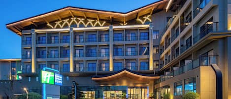 Un hotel moderno con una entrada destacada, varios pisos y una fachada bien iluminada.