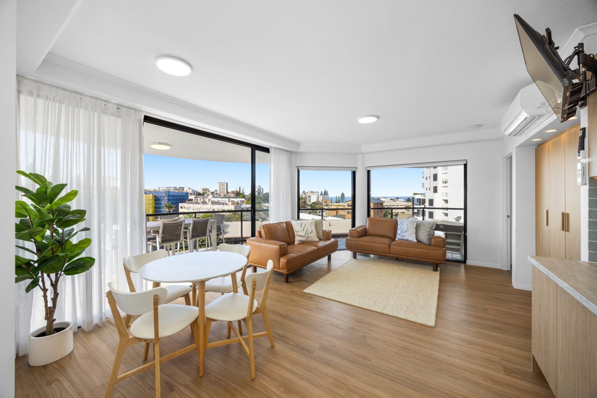 Un salon moderne comprenant un coin repas, un canapé, un téléviseur et une vue sur la ville.