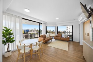 A modern living room with a dining area, a sofa, a TV, and a view of the city. - Poolside 3-Bed Retreat Near Kings Beach (Kings Beach)
