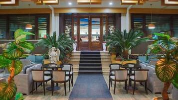 A lobby with a central staircase, seating area, and potted plants.
