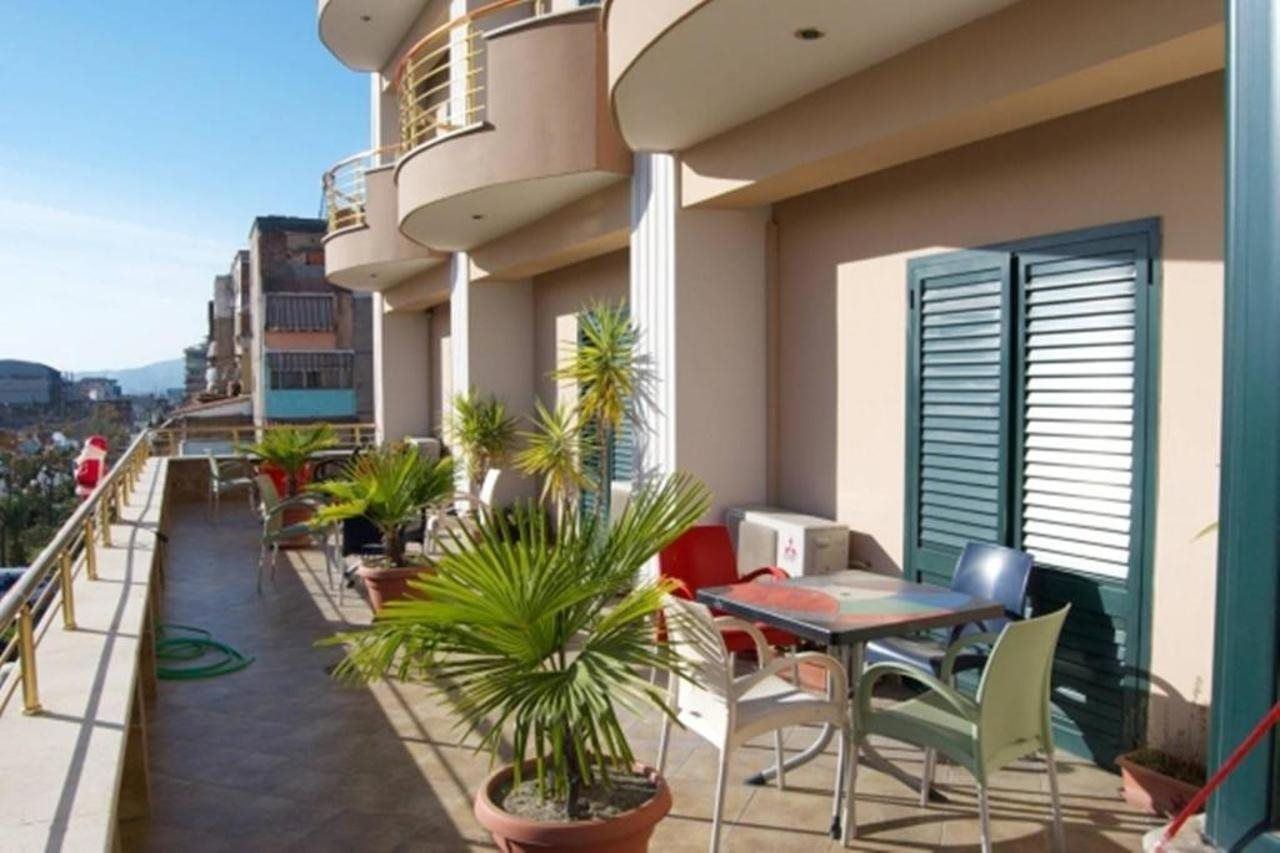 A balcony with outdoor furniture, potted plants, and a view of the city.